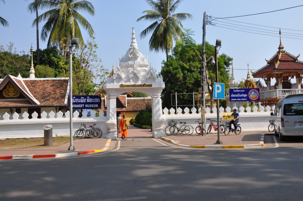 a white gate with a white wall and people walking on it