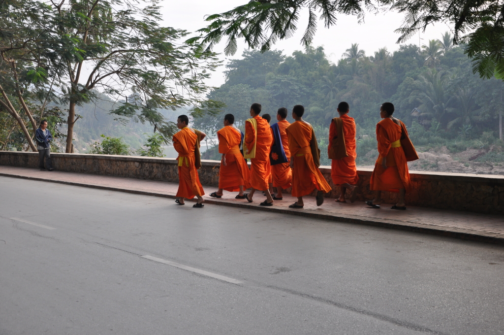 a group of people in orange robes walking on a street