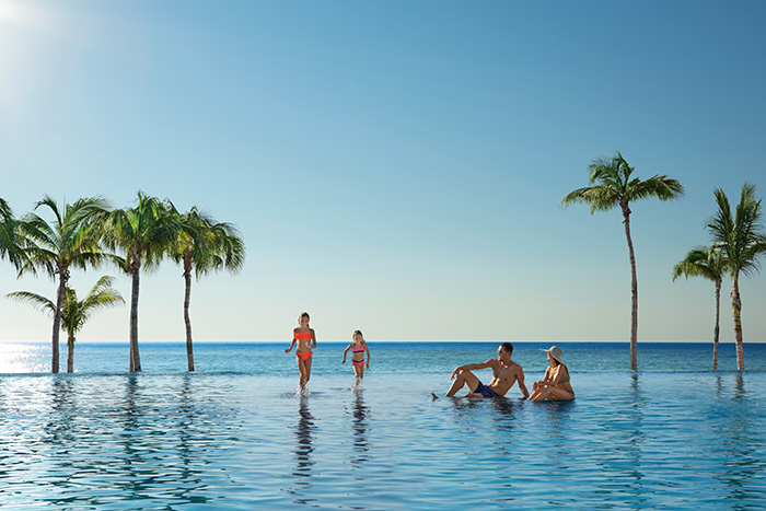 a group of people in a pool with palm trees