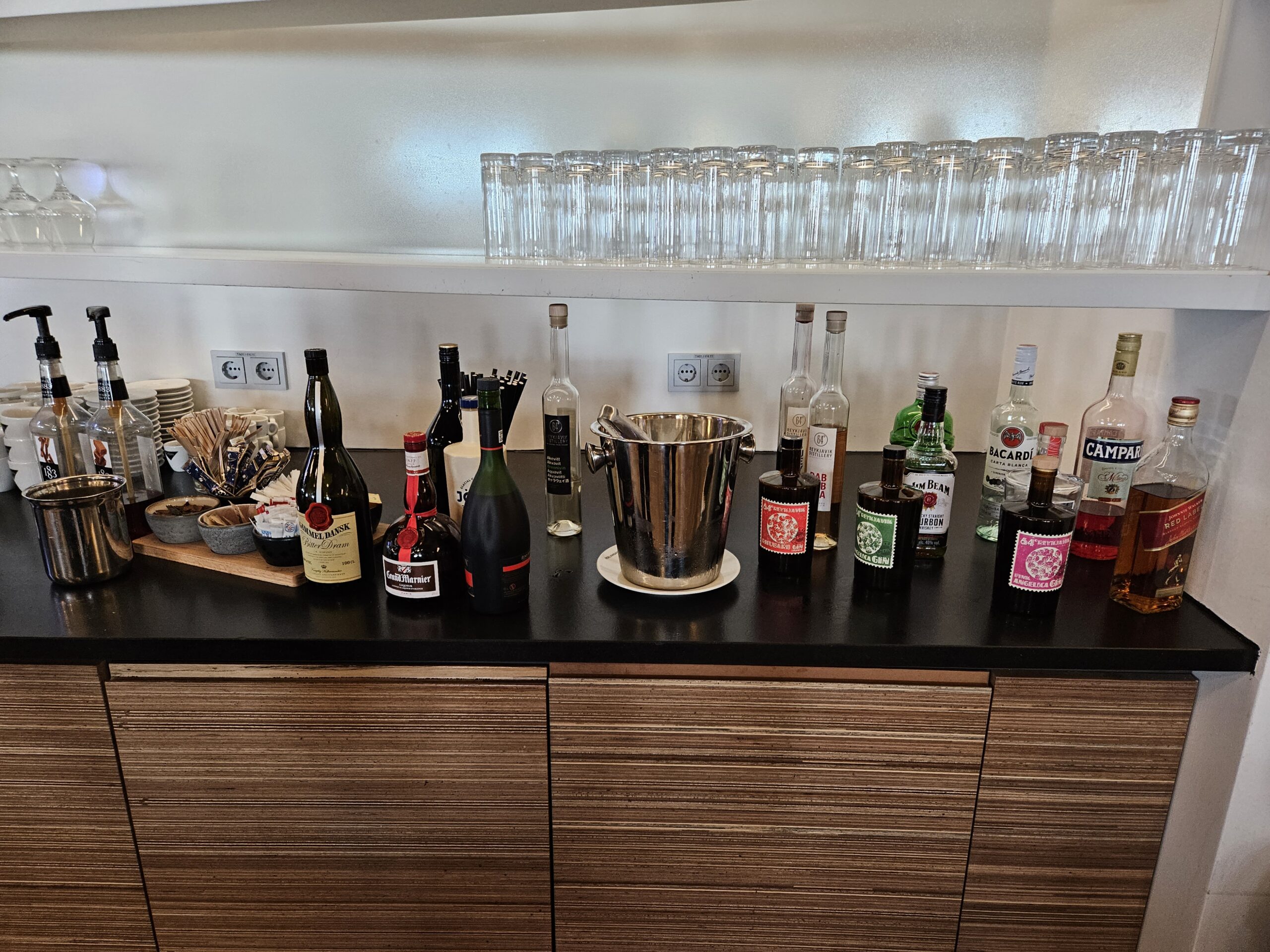 selff serve bar with bottles and glasses on it in Icelandair Saga lounge